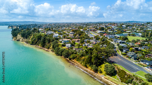 Aerial view on residential suburb on the top of rocky cliff, facing sunny harbour. Auckland, New Zealand.