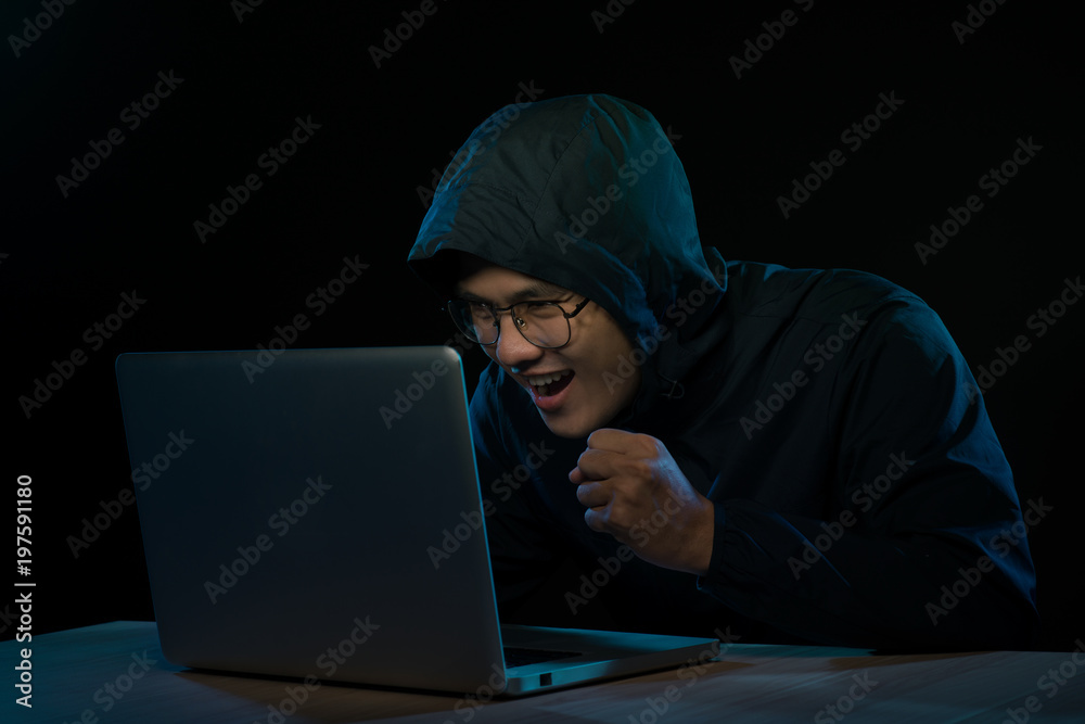 Hacker in a dark hoody sitting in front of a notebook. Computer privacy attack Hacker in a dark hoody sitting in front of a notebook. Computer privacy attack