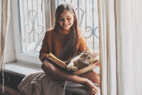 Child reading a book with cat