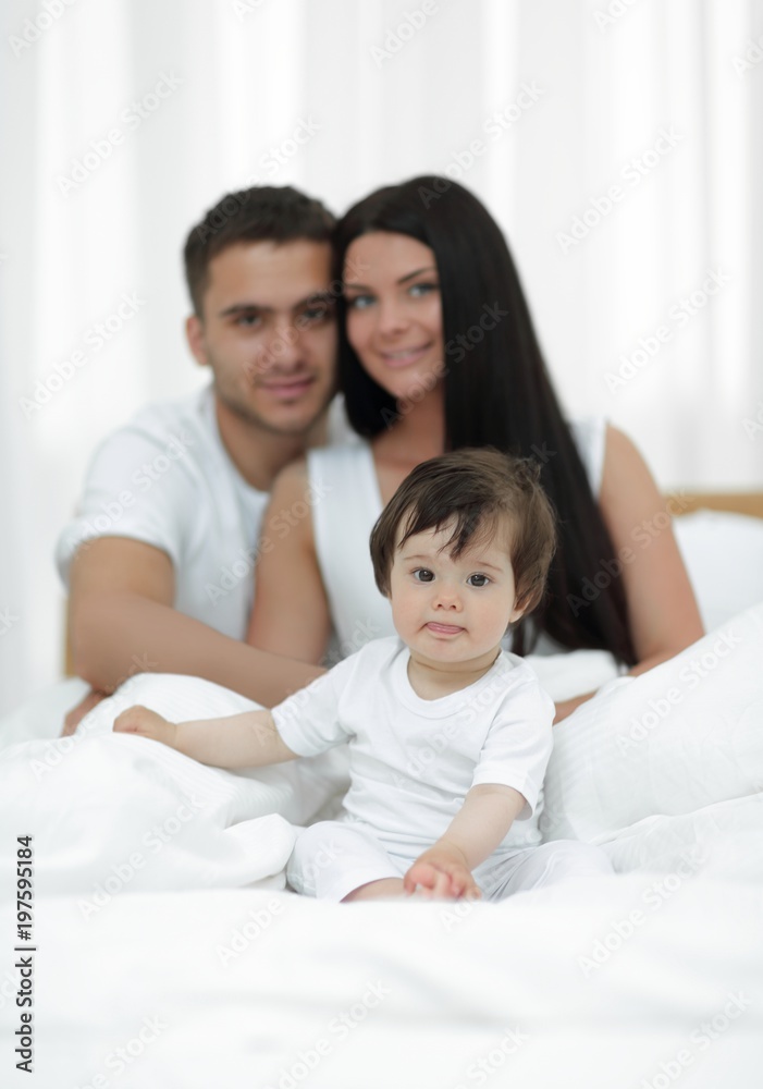 Portrait of a joyful family sitting on the bed at home