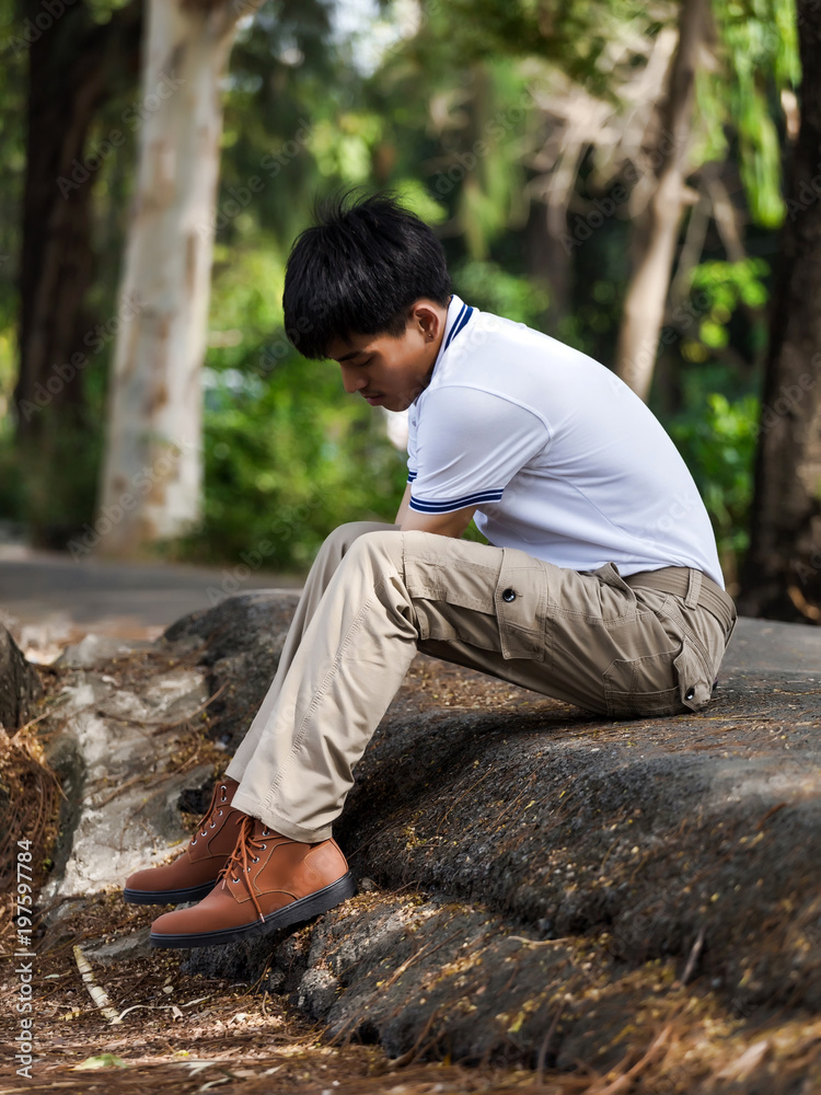 Man wearing brown cargo pants and sitting in the nature park Man wearing brown cargo pants and sitting in the nature park