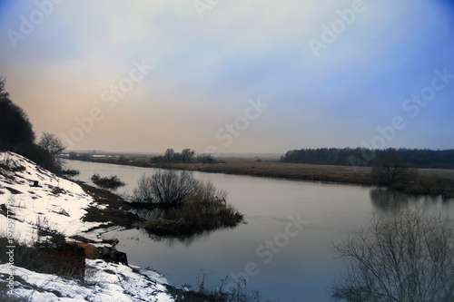 small spring river with snow along   coast