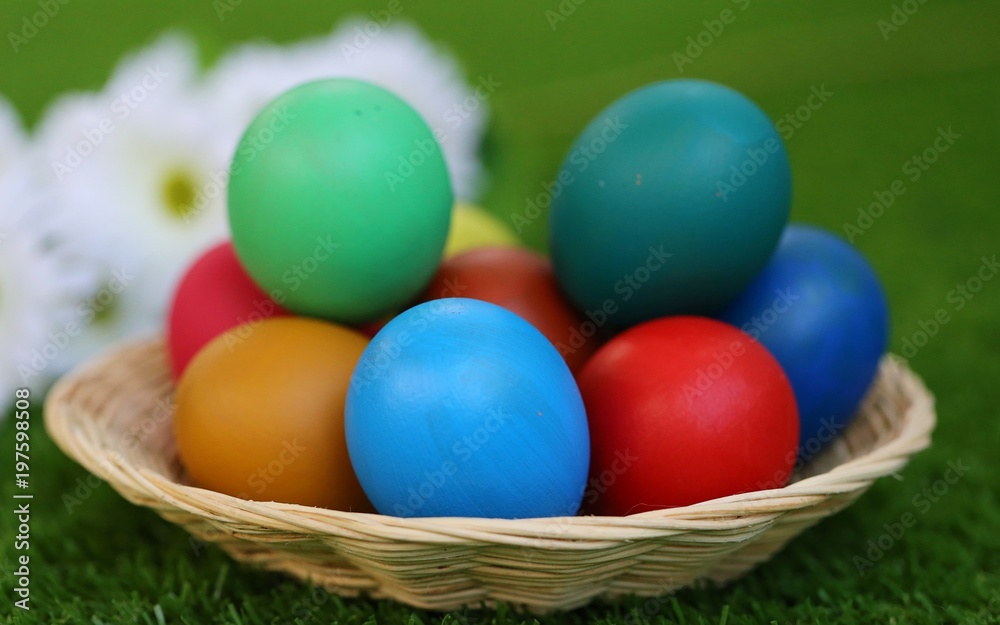 Colors Easter eggs in basket on green blur background