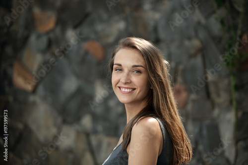 Portrait of naturally beautiful girl smiling at camera on stone background © DragonImages