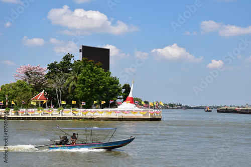 speed long tail boat in Chao Phraya river at Ko Kret with leaning stupa in background