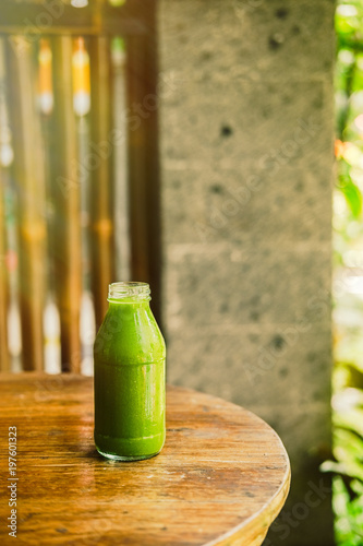 Bottle with green juice, nature background, sunny morning. Healthy eating, detoxing, juicing, fasting, body cleancing concept photo