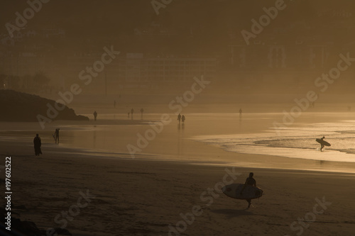 Fotografie silhouette of surfers in scenic golden sunset on hendaye beach, basque country,