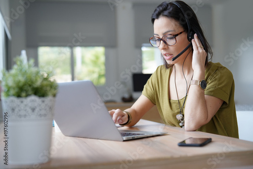 Teleoperator working in office with laptop and headset on