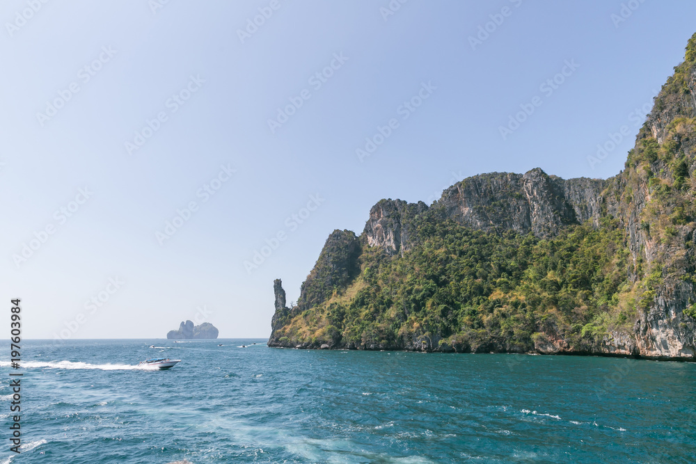 scenic view of rocky formations covered with green plants, blue sky and ocean, phi phi islands