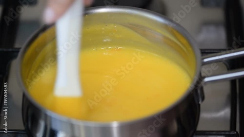 Freshly prepared lemon kurd - custard on fruit juice, in a saucepan whipped with whisk photo