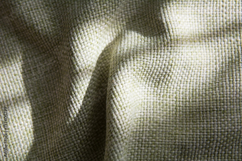 Close-up of a folded green synthetic fabric with a large thread