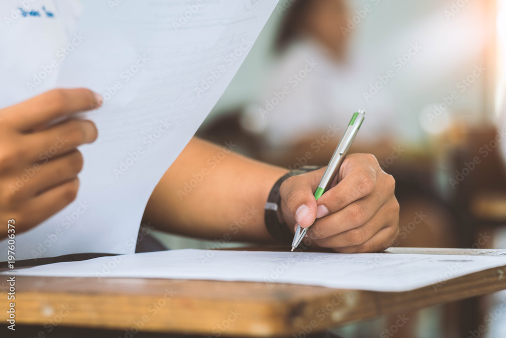 Students writing and reading exam answer sheets exercises in classroom of school with stress. Students writing and reading exam answer sheets exercises in classroom of school with stress.