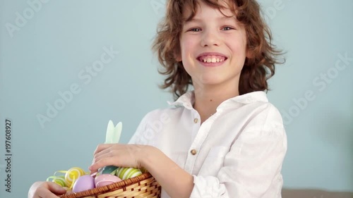 Klaus ap portrait of a curly red-haired boy with a basket of Easter eggs in his hands. Happy easter photo
