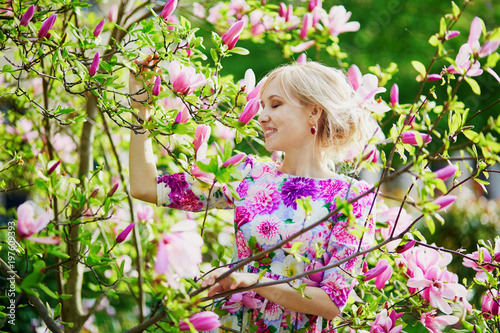 Young woman under blooming magnolia tree on a spring day