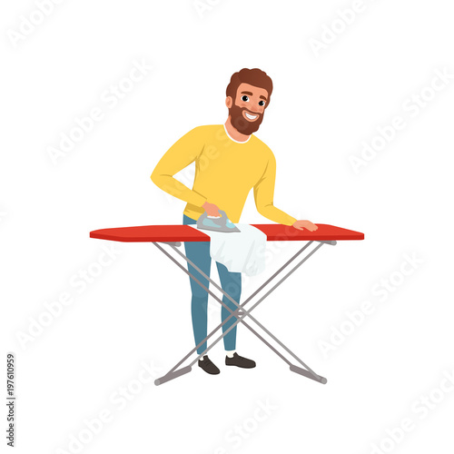 Smiling man ironing clothes on an ironing board. Cartoon house husband. Young guy in yellow sweater and blue jeans. Housekeeping theme. Flat vector design