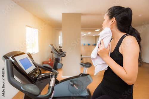Portrait of woman wipping sweat her face while cycling in the gym  Sport and gym concept