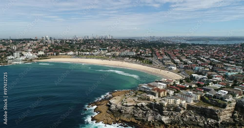 Rocky north bondi head approaching from open sea towards sandy stripe of beach with distant Sydney city CBD landmarks.
Rocky north bondi head approaching from open sea towards sandy stripe of beach with distant Sydney city CBD landmarks.