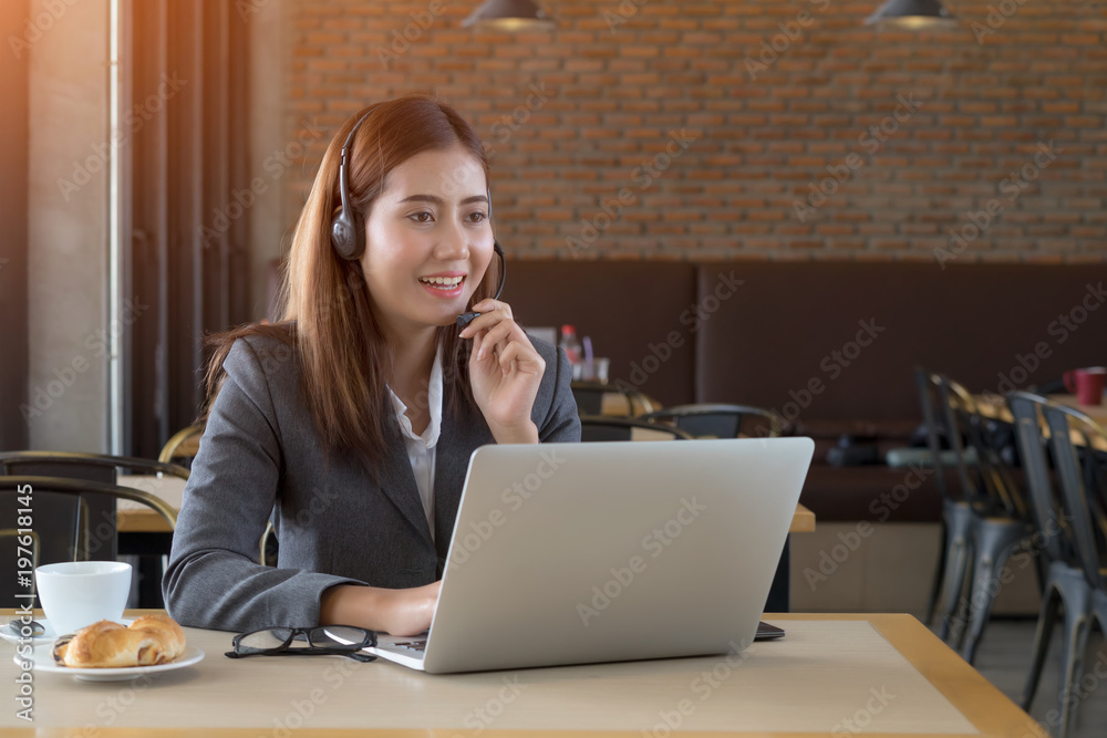 Young beautiful asian businesswoman with headset in cafe. Young beautiful asian businesswoman with headset in cafe.