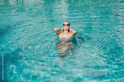 girl posing in swimsuit and sunglasses in swimming pool © LIGHTFIELD STUDIOS