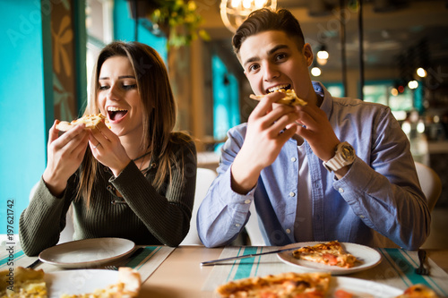 Young couple enjoying in pizza, having fun together. Consumerism, food, lifestyle concept