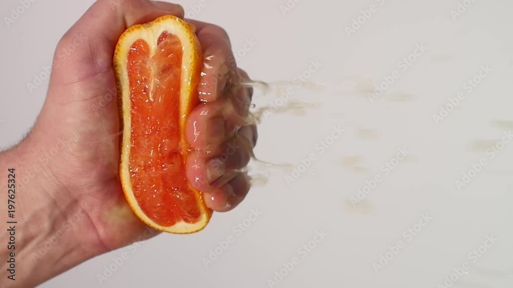 Male Hand Squeezing Fresh Orange Juice.Hand squeezing an orange Male Hand Squeezing Fresh Orange Juice.Hand squeezing an orange