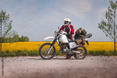 travel motorcycle off road Motorcyclist gear  A motorcycle driver looks  concept  active lifestyle  enduro  in the background a field of yellow flowers