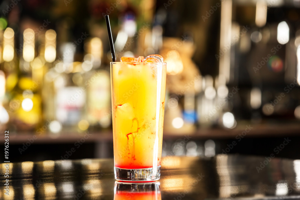 Fototapeta Closeup glass of tequila sunrise cocktail at bar background.