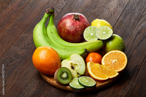 Ripe fresh fruits in a wooden plate on a rustic wooden background  selective focus  close-up  top view