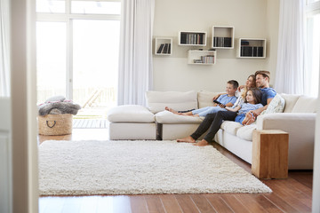 Family Sitting On Sofa At Home Watching TV Together