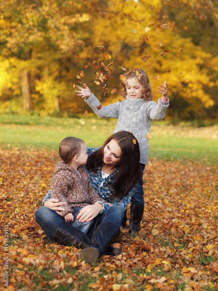 Fototapeta premium small children with mother playing in the park in autumn