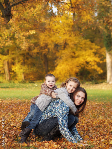 small children with mother playing in the park in autumn