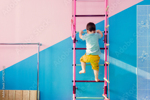 little child climbs the stairs in the gym