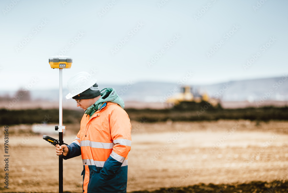 Surveyor engineer working with technology for coordinating heavy duty machinery Surveyor engineer working with technology for coordinating heavy duty machinery