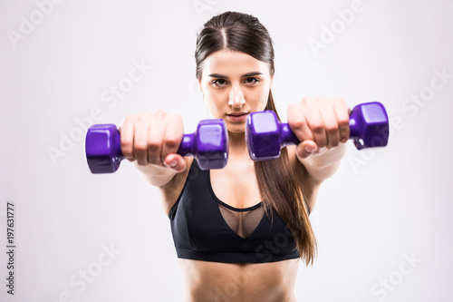 Sporty woman does the exercises with dumbbells on white background. Young woman in sportswear on white background. Strength and motivation.