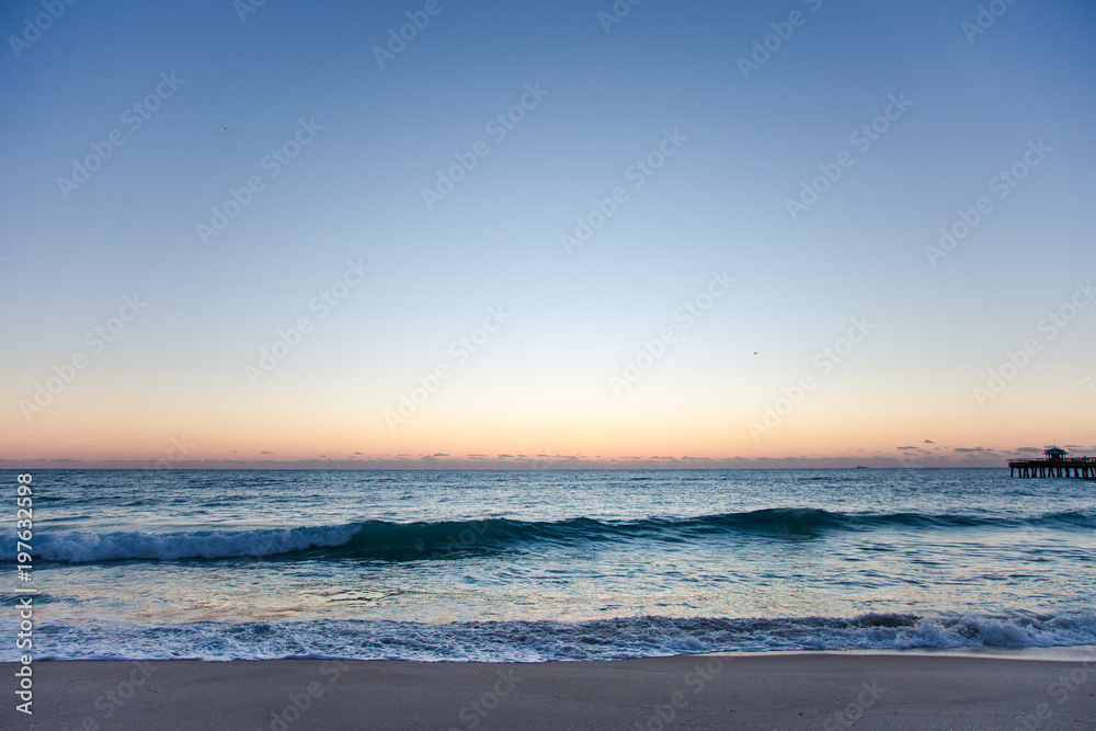 Wide Ocean Coast Beach View with Pier Silhouette at Sunrise or Sunset