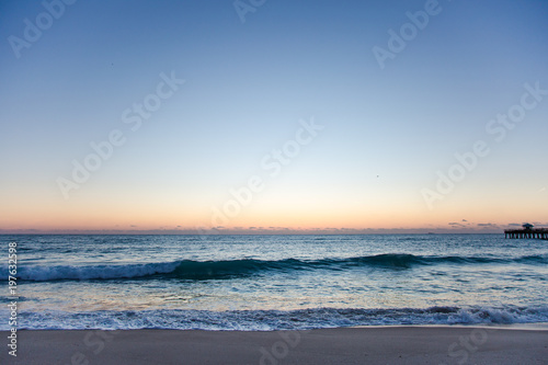 Wide Ocean Coast Beach View with Pier Silhouette at Sunrise or Sunset