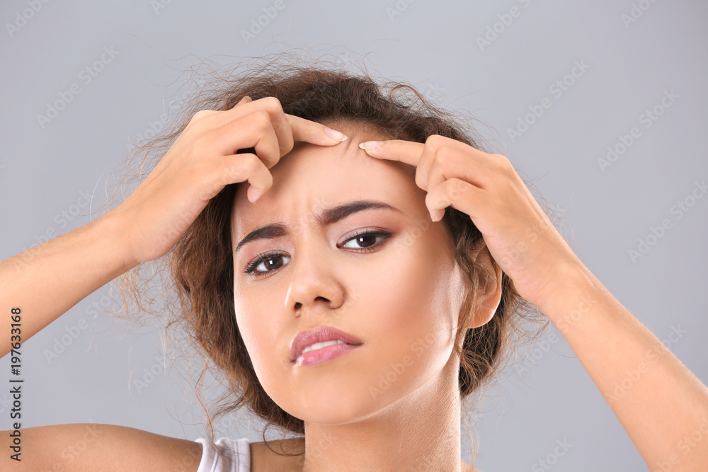 Naklejka premium Beautiful young woman with acne problem on grey background