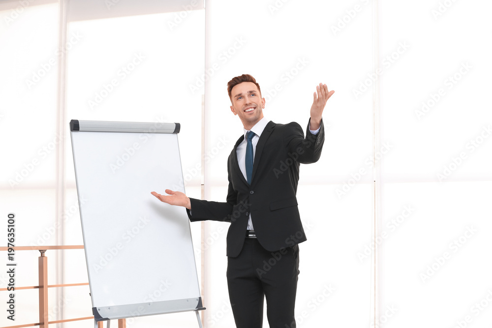 Young business trainer near flip chart, indoors Young business trainer near flip chart, indoors