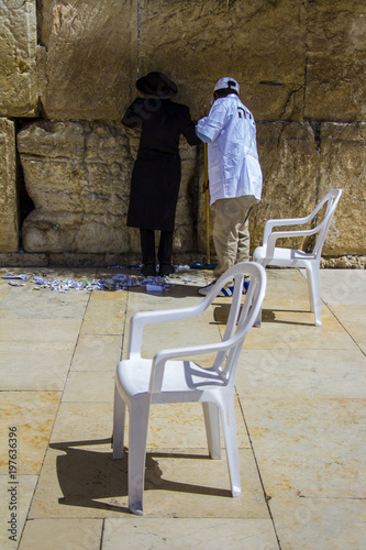 Религиозный ортодоксальный еврей молится у стены, а дворник приближается. Иерусалим, Израиль.