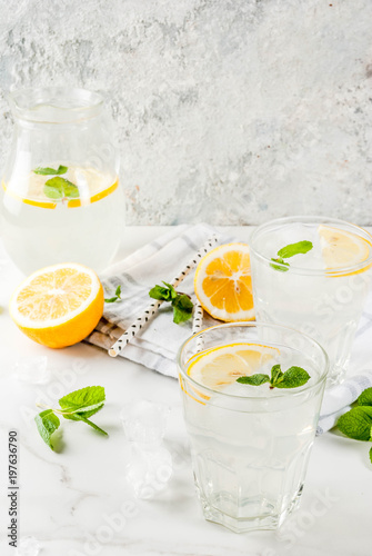 Summer refreshing drinks, mojito or lemonade with fresh mint, slices of lemon, ice, on a light background. copy space