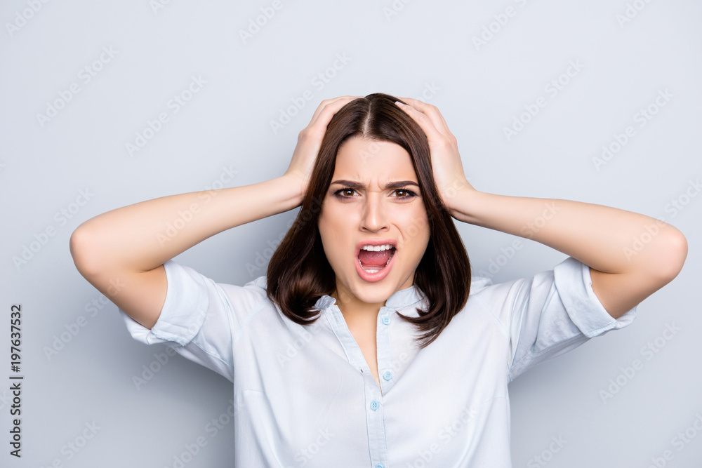 Portrait of angry, charming, pretty, stylish girl with short hair touching her head with two hands yelling looking at camera, isolated on grey background Portrait of angry, charming, pretty, stylish girl with short hair touching her head with two hands yelling looking at camera, isolated on grey background