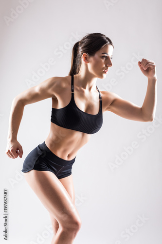Young beautiful woman in fitness wear runs isolated over white