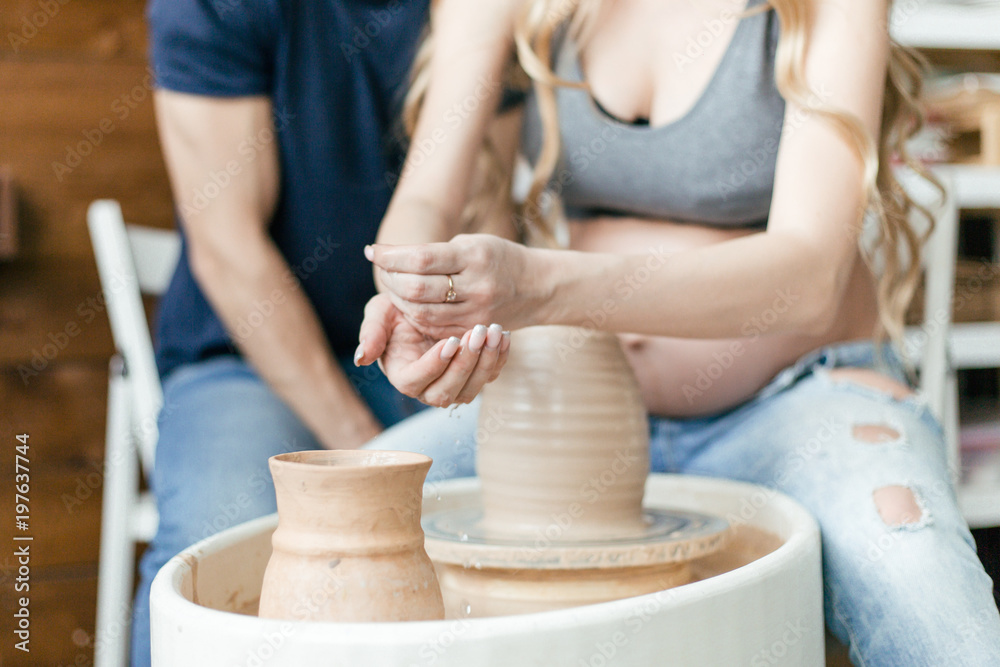 Family young couple doing ceramic pot using a pottery wheel sitting in a bright Studio