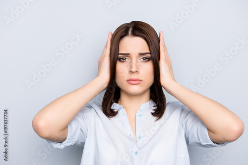 Close up portrait of charming, attractive, cute, pretty woman in shirt covering with hands her ears, she does not want to listen news, gossips, information, isolated over grey background