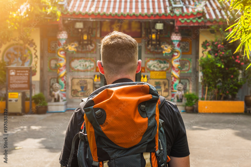 Man with backpack in the front of a buddhist chinese temple