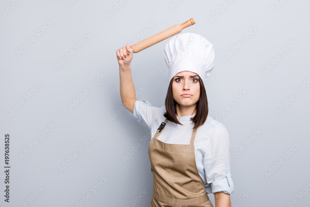 Expel penalty humorous joke bad concept. Portrait of pretty sad upset laughable annoyed irritated chef with raised wooden pin in hand wants to beat you unskilled assistant isolated on gray background Expel penalty humorous joke bad concept. Portrait of pretty sad upset laughable annoyed irritated chef with raised wooden pin in hand wants to beat you unskilled assistant isolated on gray background