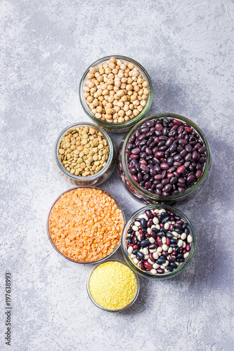 Dry legumes in glass jars on stone background, vegetarian protein source. Top view, space for text.