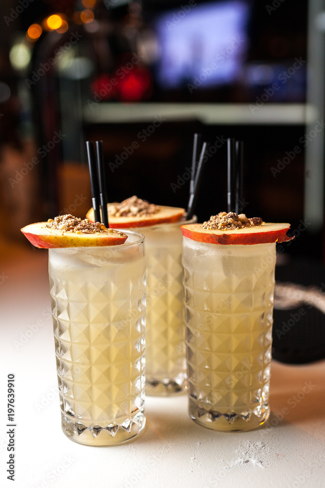 Group orange cocktails with apple and cinamon on the white bar Group orange cocktails with apple and cinamon on the white bar