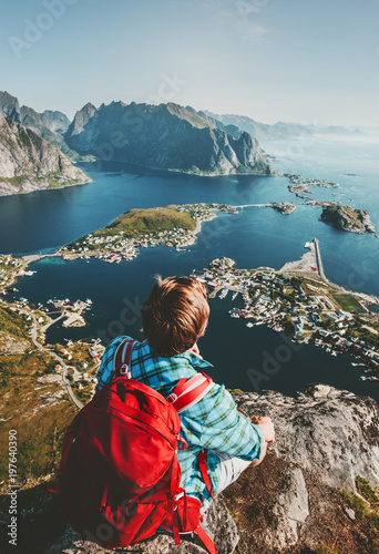 Man traveling in Norway sitting on cliff edge lifestyle adventure outdoor summer vacations  enjoying aerial view of Lofoten islands