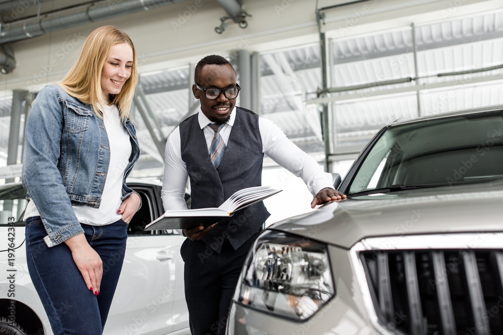 Sales consultant shows the girl a new car to buy Sales consultant shows the girl a new car to buy